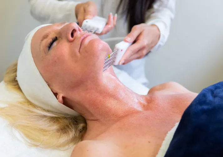 Twin Neurotris microcurrent probes being worked along a client’s jawline and neck during a facelifting treatment